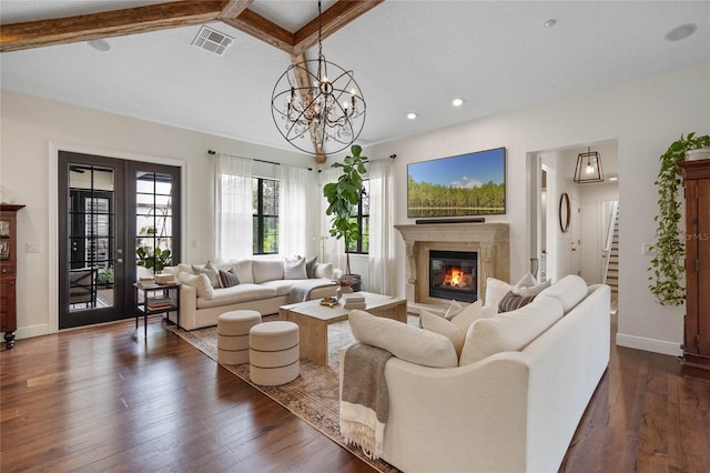 living room featuring baseboards, visible vents, dark wood-type flooring, a glass covered fireplace, and a chandelier