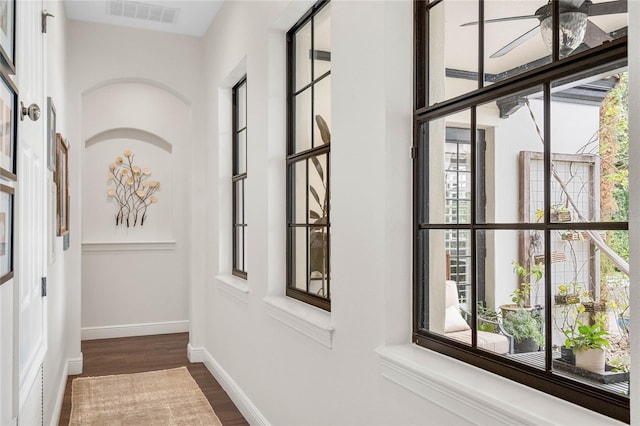 hallway featuring visible vents, baseboards, and dark wood-style floors