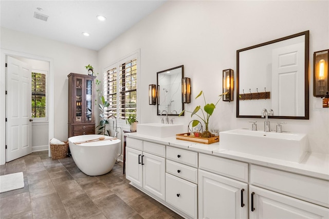 bathroom featuring double vanity, recessed lighting, a freestanding bath, and a sink