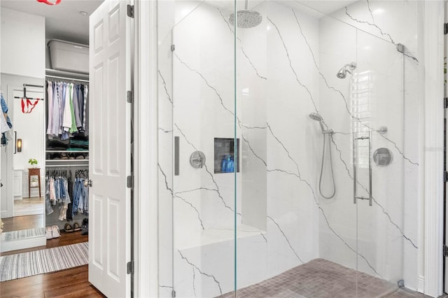 bathroom with a marble finish shower, wood finished floors, and a spacious closet