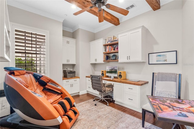 office space featuring a ceiling fan, wood finished floors, visible vents, built in study area, and beam ceiling