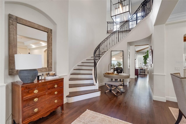 entryway with stairway, baseboards, dark wood-style flooring, and arched walkways