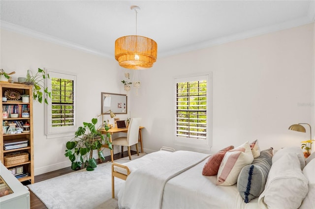 bedroom with multiple windows, crown molding, baseboards, and wood finished floors