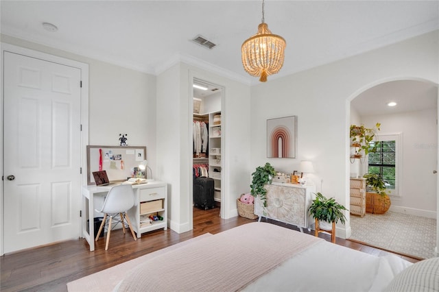 bedroom featuring wood finished floors, visible vents, arched walkways, a spacious closet, and a chandelier