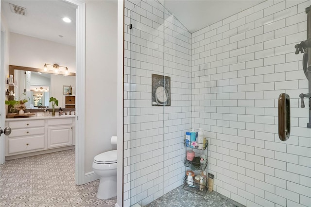 full bath featuring tiled shower, toilet, vanity, and visible vents