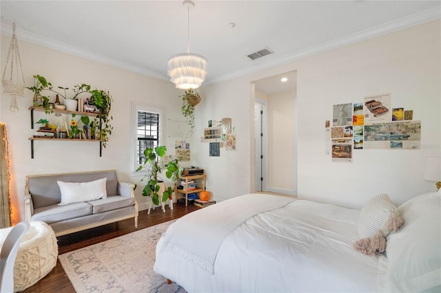 bedroom with crown molding, a notable chandelier, wood finished floors, and visible vents