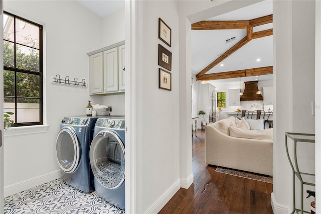 clothes washing area featuring wood finished floors, visible vents, baseboards, cabinet space, and washer and dryer