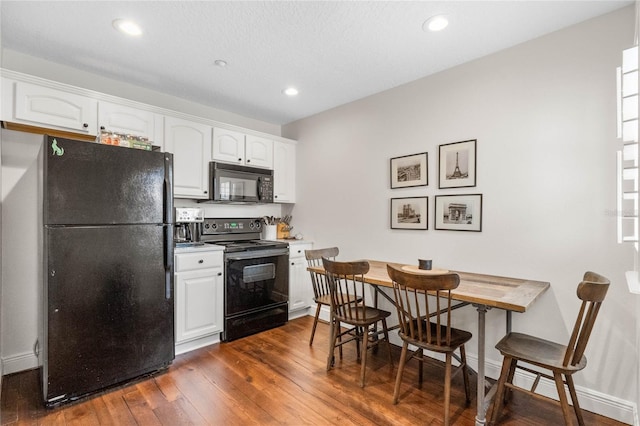 kitchen with black appliances, white cabinets, dark wood-style floors, and baseboards