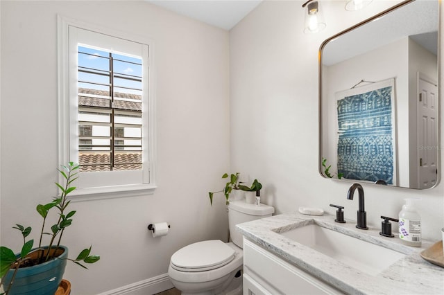 bathroom with baseboards, toilet, and vanity