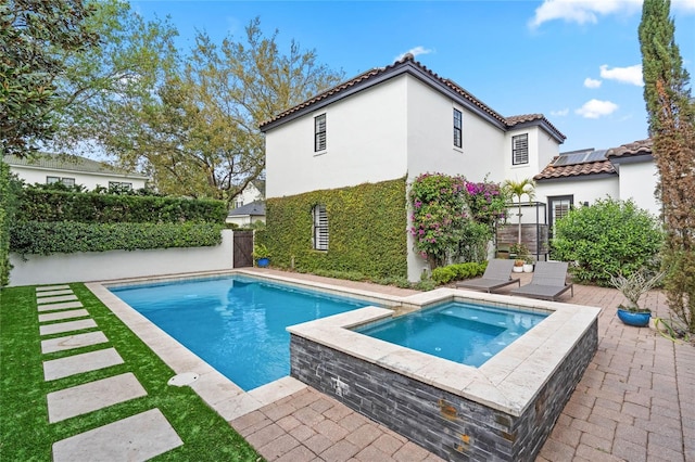 outdoor pool with an in ground hot tub, a patio area, and a fenced backyard