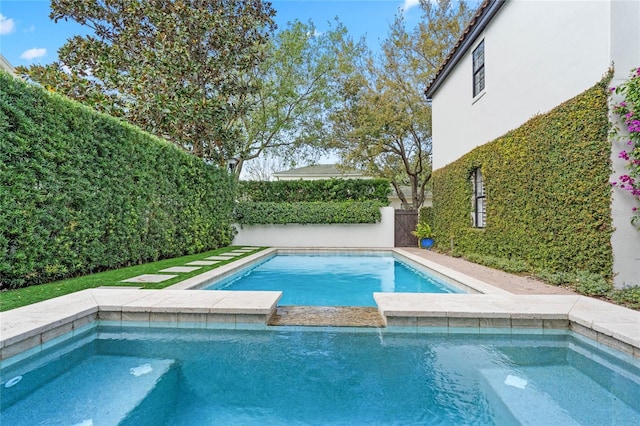 view of swimming pool with a fenced backyard and a pool with connected hot tub