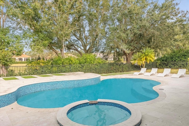 view of swimming pool with a patio, fence, and a pool with connected hot tub