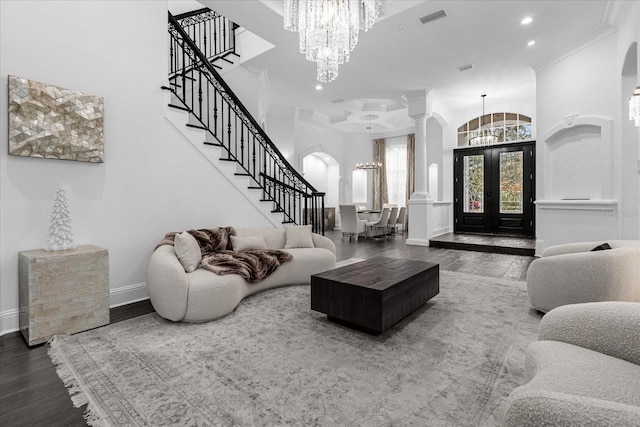 living room featuring stairway, wood finished floors, visible vents, crown molding, and a notable chandelier