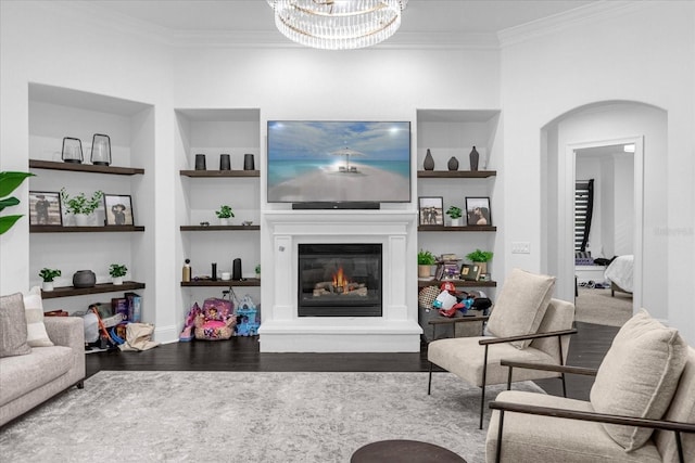 living area with arched walkways, built in features, crown molding, and wood finished floors