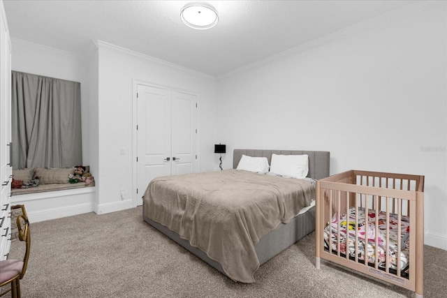 carpeted bedroom featuring a closet, baseboards, and crown molding