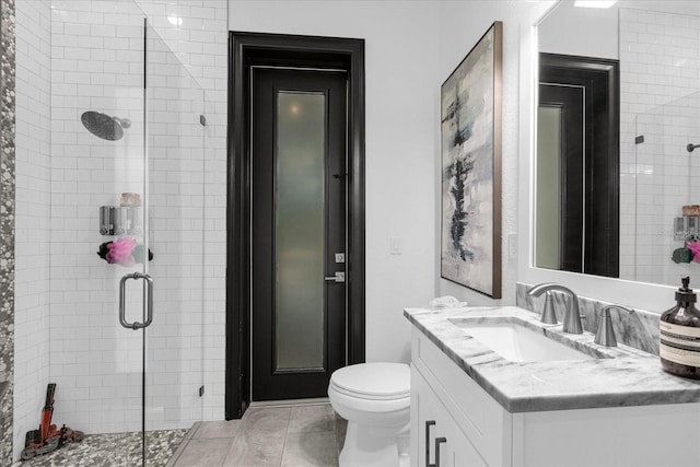 bathroom with vanity, a shower stall, toilet, and tile patterned floors