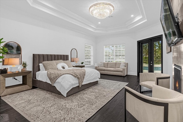 bedroom with dark wood finished floors, a tray ceiling, ornamental molding, an inviting chandelier, and access to outside