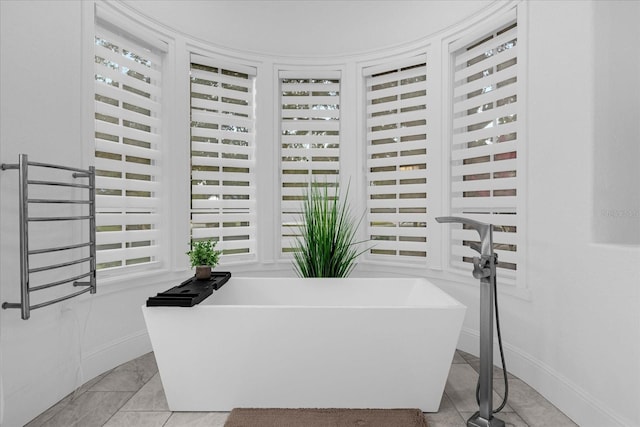 full bathroom with tile patterned floors, a freestanding tub, and baseboards