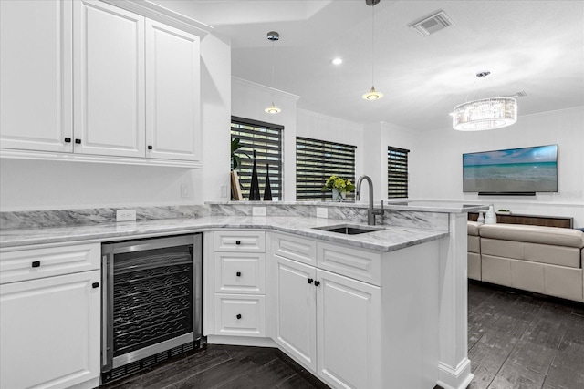 kitchen featuring visible vents, beverage cooler, dark wood finished floors, a peninsula, and a sink