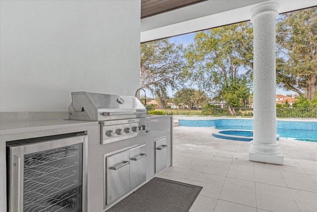 view of patio featuring wine cooler, grilling area, exterior kitchen, and a fenced backyard