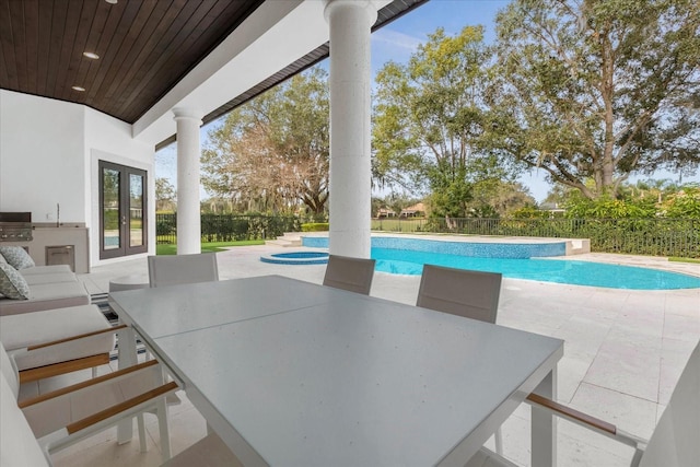 view of pool with a patio area, outdoor dining space, french doors, and an in ground hot tub