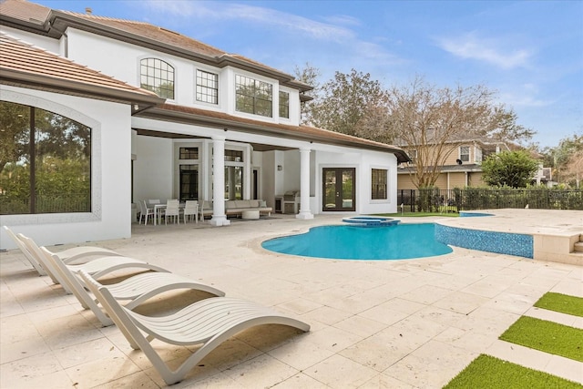 view of pool featuring fence, a pool with connected hot tub, french doors, outdoor lounge area, and a patio area