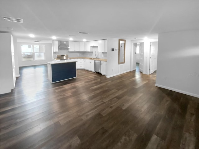 kitchen featuring a center island, dark wood-type flooring, light countertops, stainless steel appliances, and wall chimney exhaust hood