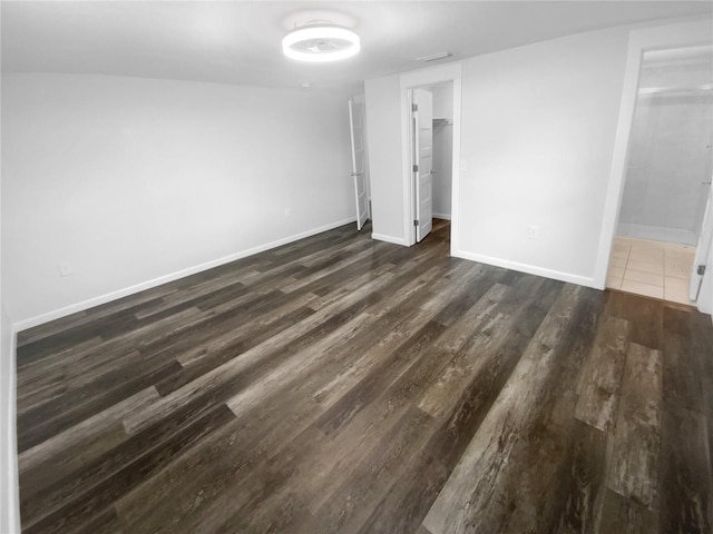 unfurnished room with baseboards and dark wood-style flooring