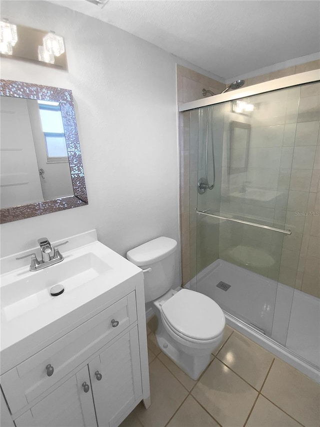 bathroom with tile patterned flooring, a stall shower, toilet, and vanity