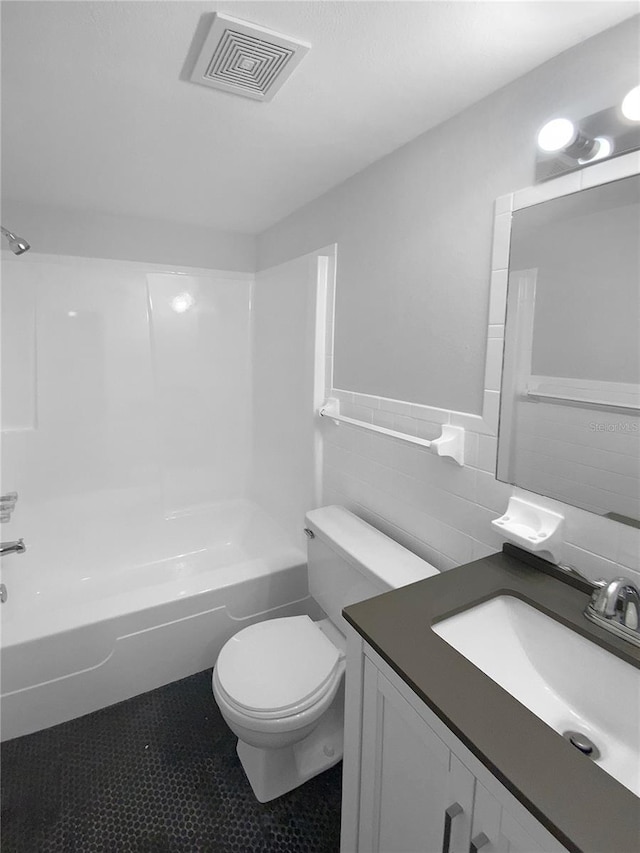 full bathroom with vanity, visible vents, shower / washtub combination, tile walls, and toilet