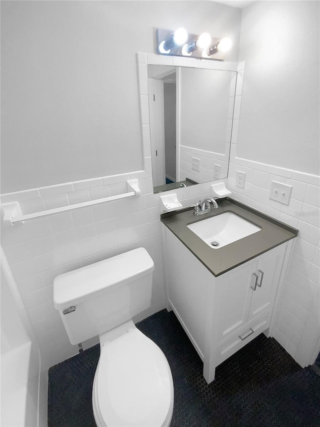 bathroom with vanity, tile walls, toilet, and wainscoting