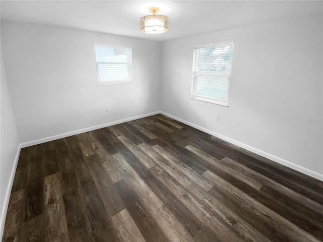 spare room with plenty of natural light, baseboards, and dark wood-style flooring