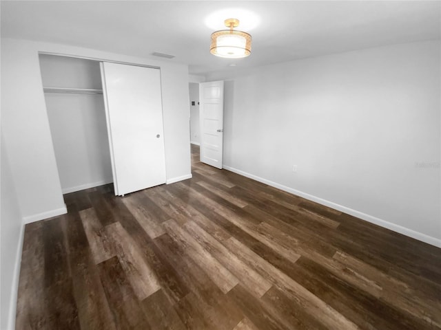 unfurnished bedroom featuring a closet, baseboards, and dark wood-type flooring