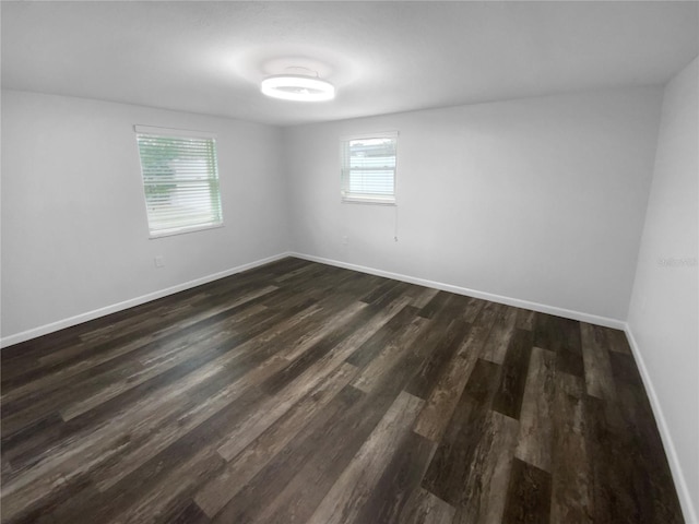 unfurnished room with dark wood finished floors and baseboards