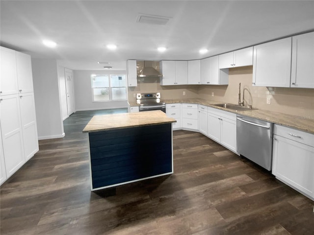 kitchen featuring visible vents, a sink, stainless steel appliances, dark wood-type flooring, and wall chimney range hood