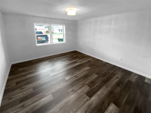 empty room featuring dark wood-style floors and baseboards