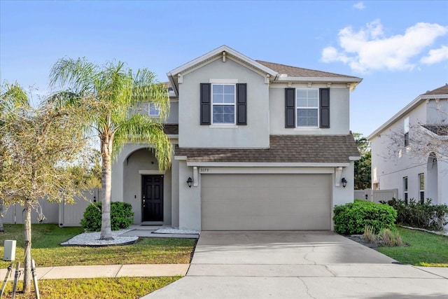 traditional-style house featuring a shingled roof, fence, concrete driveway, stucco siding, and a garage