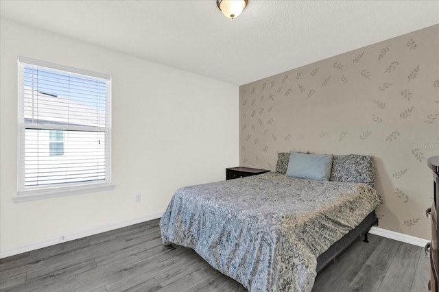 bedroom with baseboards, light wood-style flooring, and wallpapered walls