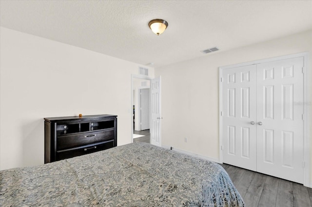 bedroom with wood finished floors, visible vents, and a closet