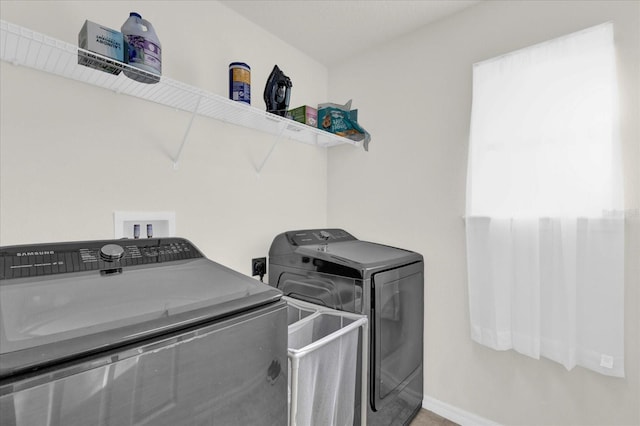 laundry area with laundry area, separate washer and dryer, and baseboards