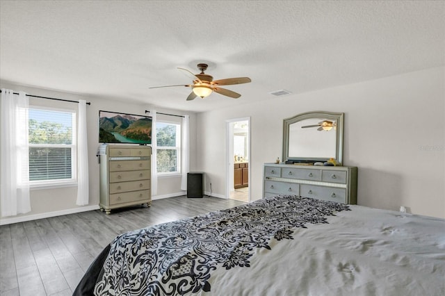 bedroom with visible vents, a ceiling fan, a textured ceiling, wood finished floors, and baseboards