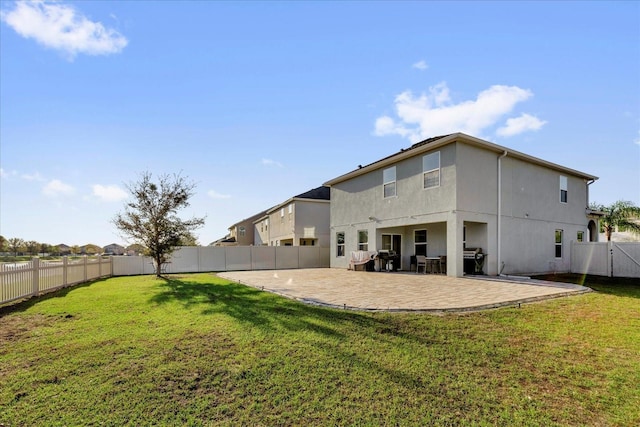 rear view of house featuring a yard, a patio, a fenced backyard, and stucco siding