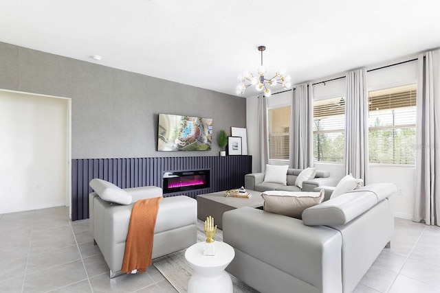 living area featuring light tile patterned floors, a notable chandelier, baseboards, and a glass covered fireplace