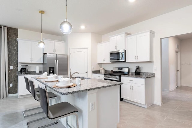 kitchen with a kitchen island with sink, a sink, a kitchen breakfast bar, white cabinetry, and stainless steel appliances