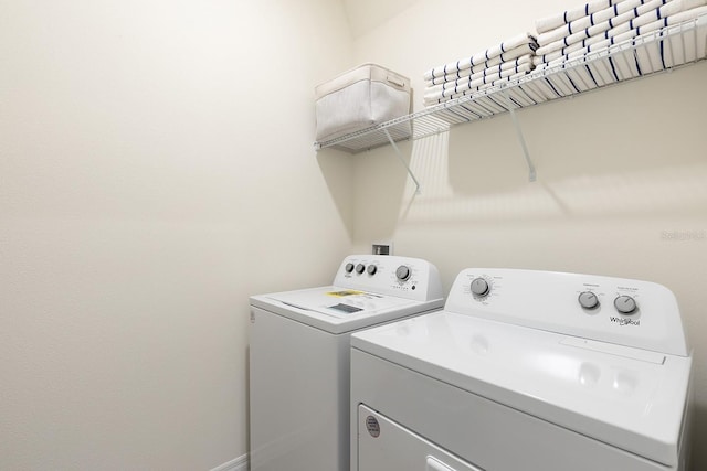 clothes washing area with laundry area, baseboards, and washing machine and clothes dryer