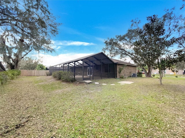 view of yard featuring a lanai, central air condition unit, and fence