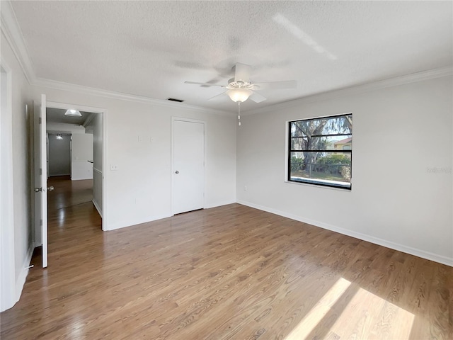 unfurnished bedroom featuring wood finished floors, baseboards, visible vents, ornamental molding, and a textured ceiling