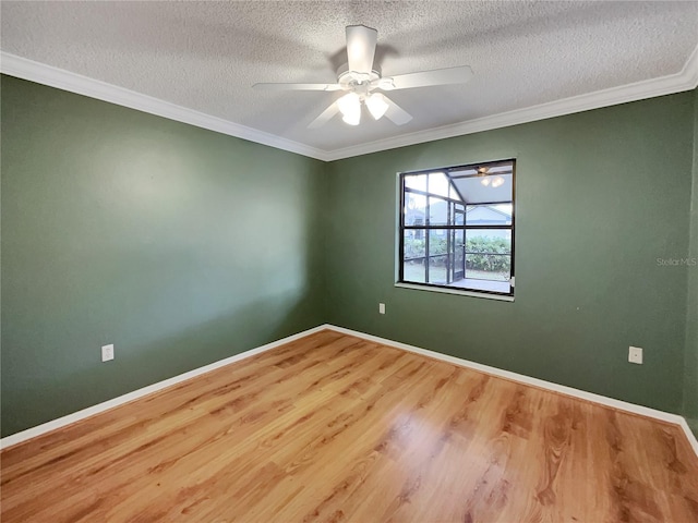 empty room with baseboards, crown molding, a ceiling fan, and wood finished floors