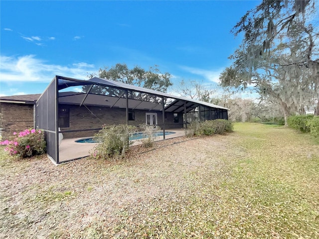 back of house with a lanai, a yard, a patio area, and an outdoor pool