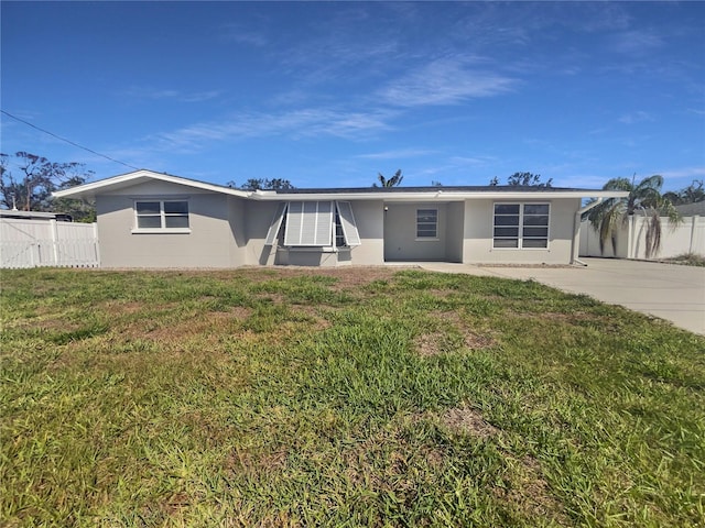 rear view of property featuring stucco siding, a lawn, and fence